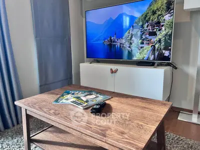 Modern living room with sleek TV and wooden coffee table in cozy apartment.