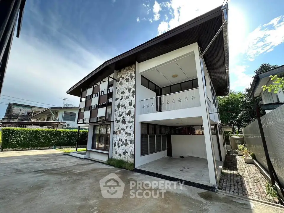 Stunning modern two-story house with unique stone facade and spacious driveway.