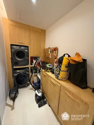 Compact laundry room with stacked washer and dryer, ample storage cabinets, and modern design.