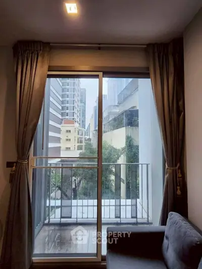 Modern apartment with balcony view in urban setting, featuring large windows and stylish curtains.