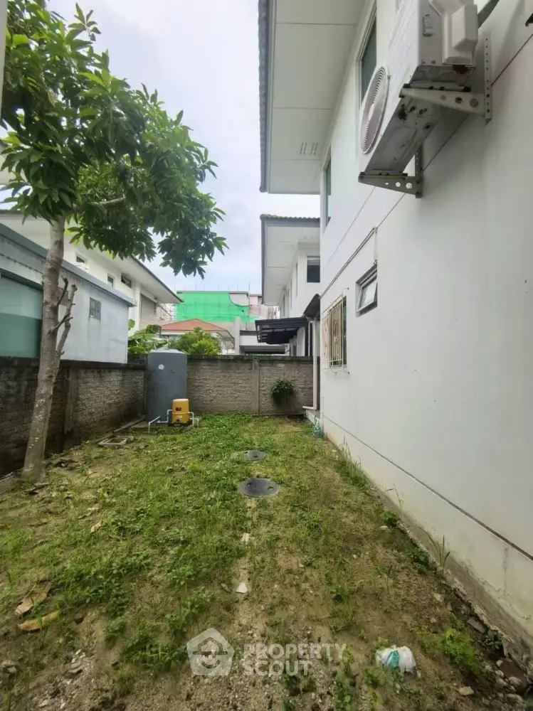 Charming side yard with air conditioning unit and lush greenery, perfect for outdoor relaxation.