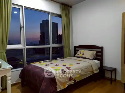 Cozy bedroom with city view, featuring a single bed and large window for natural light.