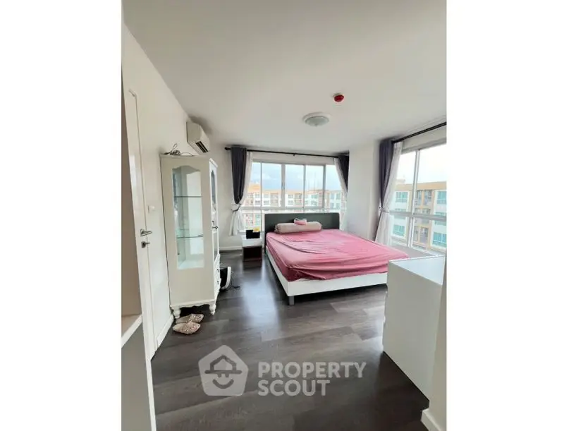 Spacious bedroom with large windows and modern decor in a high-rise apartment.