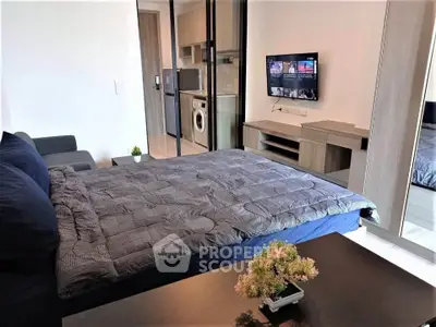 Modern studio apartment with cozy bed, sleek furniture, and in-unit washing machine for convenient living.