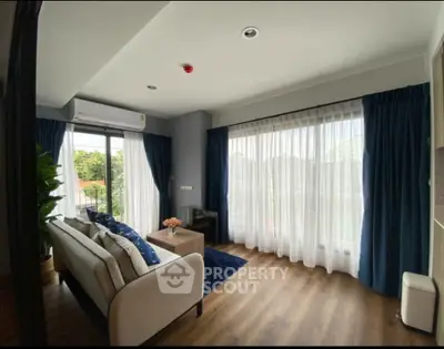 Spacious living room with large windows and modern decor, offering a bright and inviting atmosphere.
