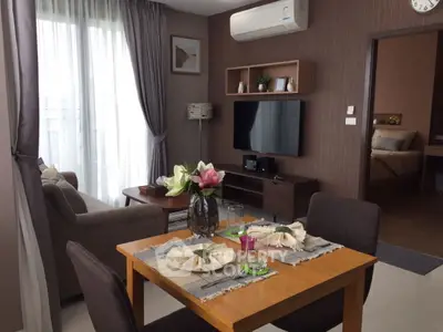 Modern living room with dining area, featuring elegant decor and natural light.