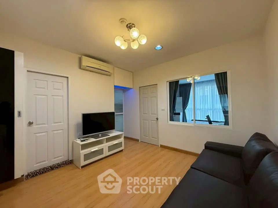Modern living room with sleek black sofa and mounted TV in stylish apartment.