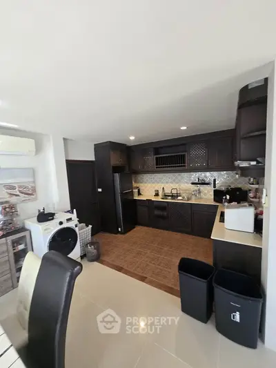 Modern kitchen with dark cabinets and washing machine in open layout