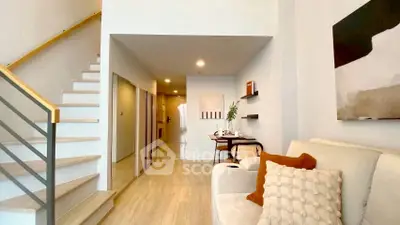 Modern living room with staircase and stylish decor in a bright, open layout apartment.