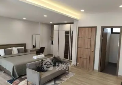 Spacious modern bedroom with cozy seating area and stylish decor