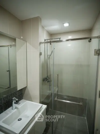 Modern bathroom with sleek shower enclosure and stylish sink in contemporary apartment.