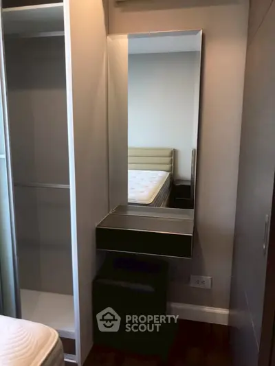 Compact bedroom with built-in wardrobe and mirror, showcasing efficient space utilization.