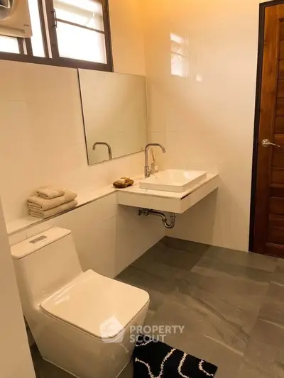 Modern bathroom with sleek fixtures and natural light, featuring a stylish sink and toilet.