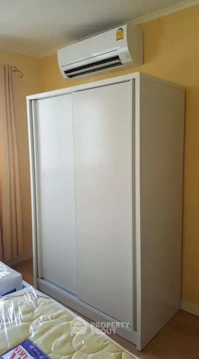 Modern bedroom with sleek white wardrobe and air conditioning unit