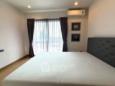 Spacious bedroom with modern decor and large window offering natural light.