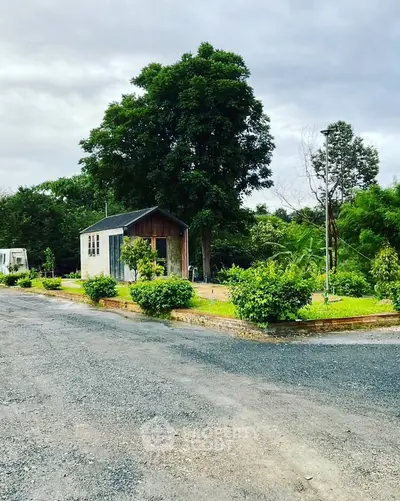 Charming small house with lush greenery and spacious outdoor area, perfect for serene living.