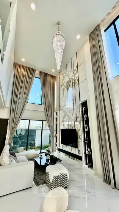 Luxurious high-ceiling living room with elegant chandelier and modern decor