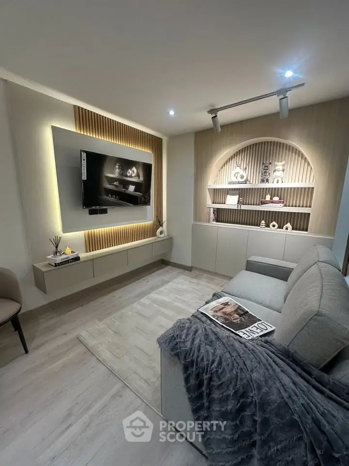 Modern living room with stylish decor and built-in shelving, featuring a wall-mounted TV and cozy seating area.