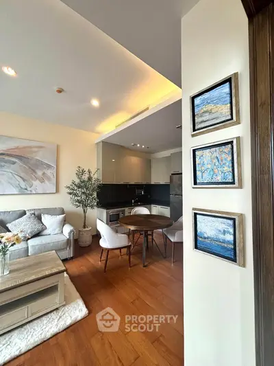Modern open-plan living room with stylish decor and cozy seating area, featuring elegant artwork and wooden flooring.