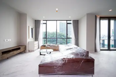 Spacious modern living room with large windows and city view, featuring elegant furniture and natural light.