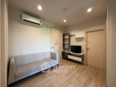 Modern living room with sleek furniture and wooden flooring, featuring a cozy sofa and wall-mounted TV.