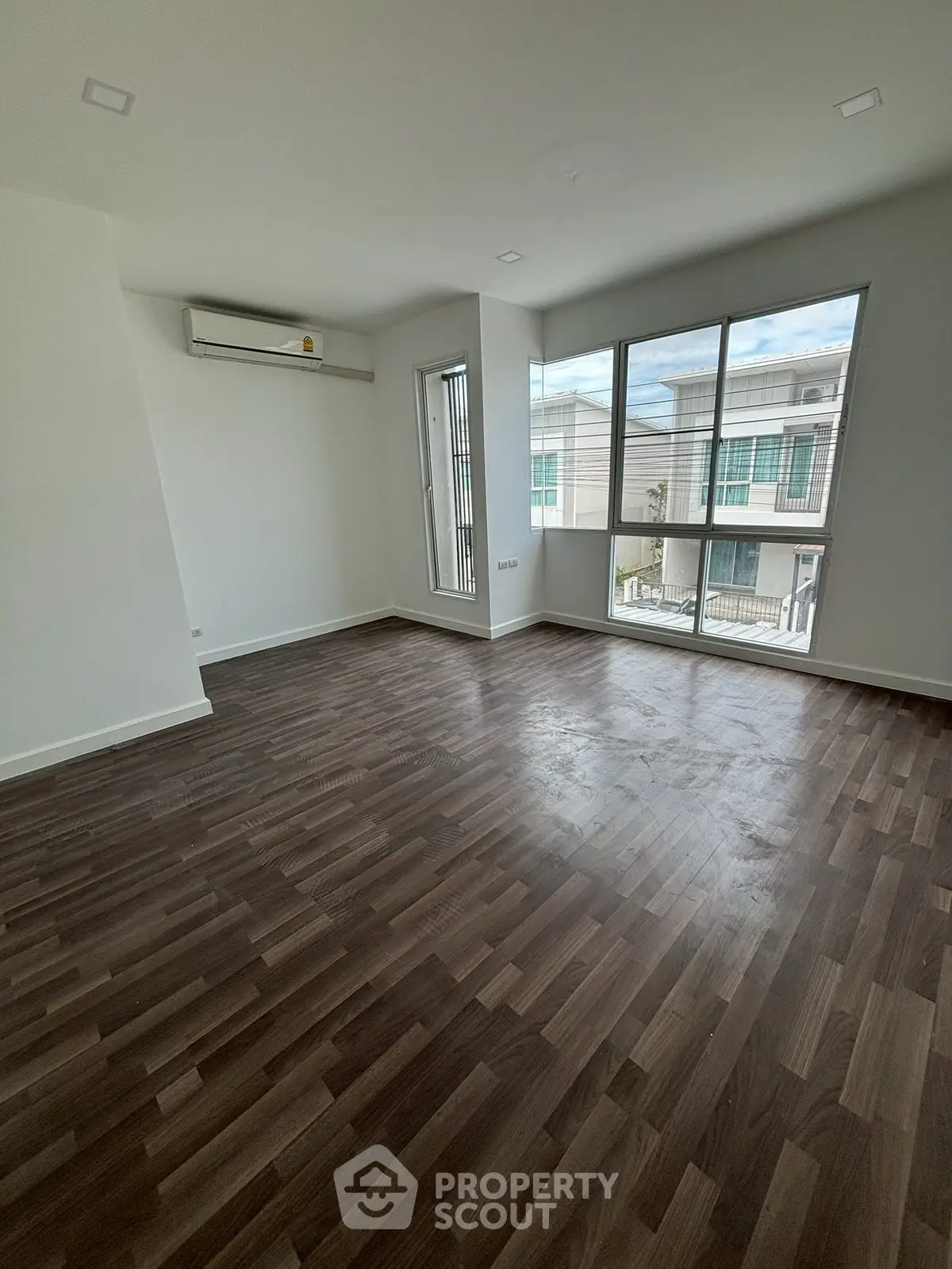 Spacious empty room with large windows and wooden flooring, perfect for customization.