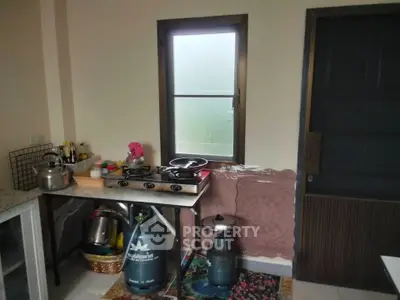 Cozy kitchen with gas stove and window, featuring compact layout and essential appliances.