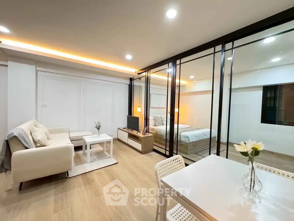 Modern open-plan living room with cozy seating and elegant bedroom view.