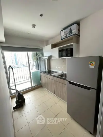 Modern kitchen with balcony view, featuring sleek appliances and ample storage in a stylish urban apartment.