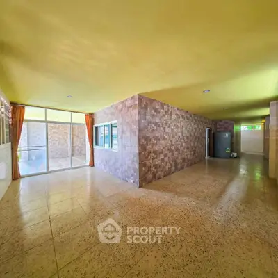 Spacious open-plan living area with large windows and tiled flooring