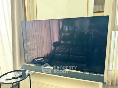 Modern living room with large flat-screen TV and leather sofa, perfect for entertainment.