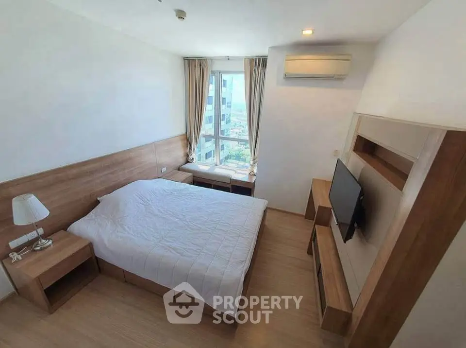 Modern bedroom with wooden furniture and city view window, featuring a cozy bed and mounted TV.