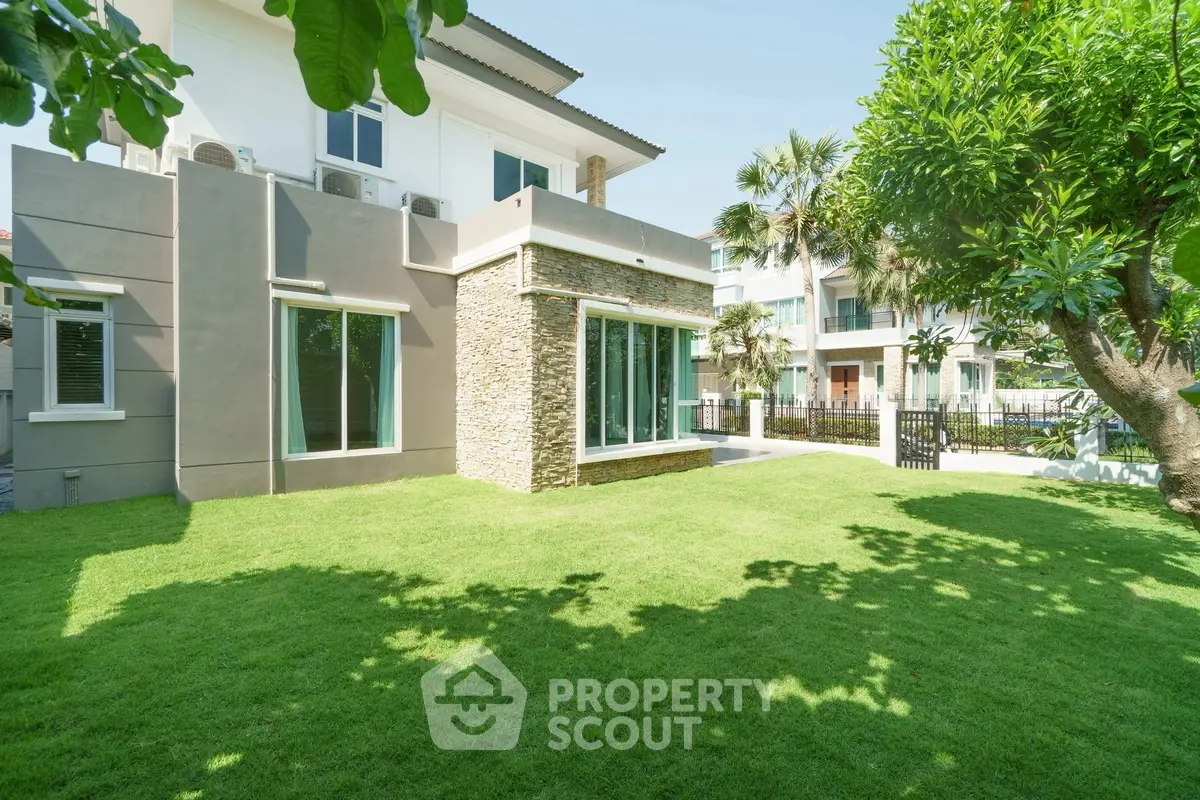 Luxurious modern home with spacious green lawn and elegant exterior design, perfect for family living.