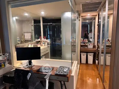 Modern bathroom with glass partition and workspace, featuring sleek design and ample storage.