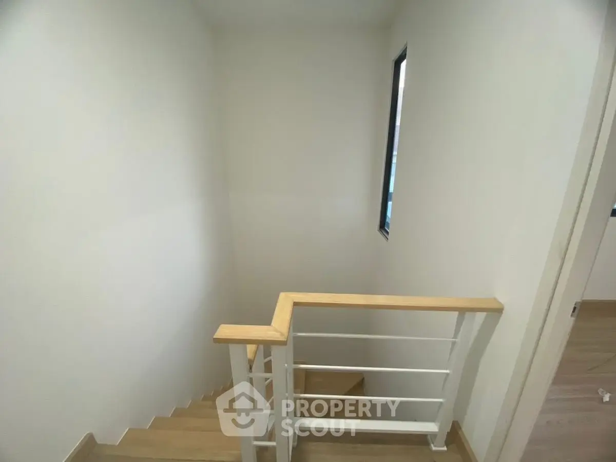 Modern staircase with wooden handrail and minimalist design in a bright home interior.