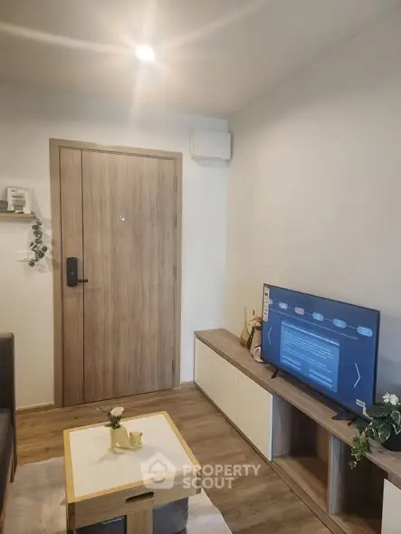 Modern living room with wooden door, sleek TV setup, and stylish decor.