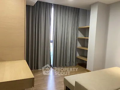 Modern minimalist room with wooden flooring and built-in shelves, featuring elegant curtains and a cozy ambiance.