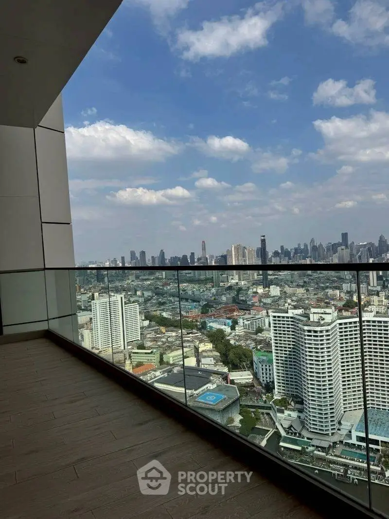 Stunning cityscape view from a high-rise balcony with glass railing and wooden flooring.