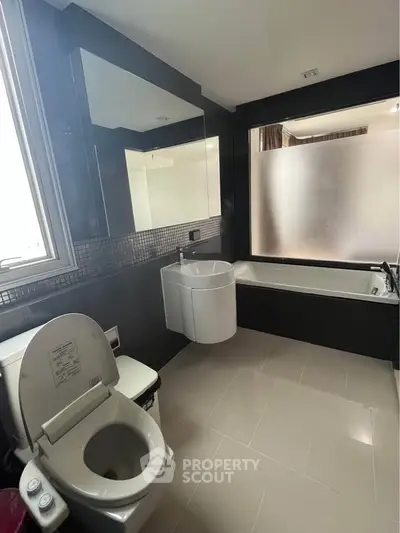Modern bathroom with sleek fixtures and large frosted glass window, featuring a bathtub and stylish sink.