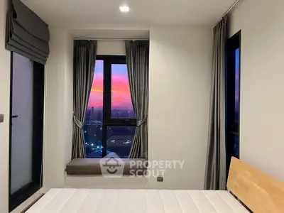 Modern bedroom with stunning sunset view through large windows, featuring elegant curtains and a cozy window seat.