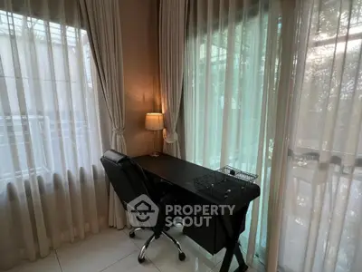 Elegant study room with ample natural light, featuring a sleek black desk, comfortable office chair, and floor-to-ceiling sheer curtains.