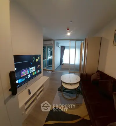 Modern living room with sleek TV setup and cozy seating area in stylish apartment.