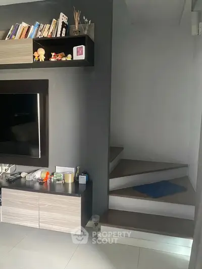 Modern living room with sleek TV setup and stylish staircase