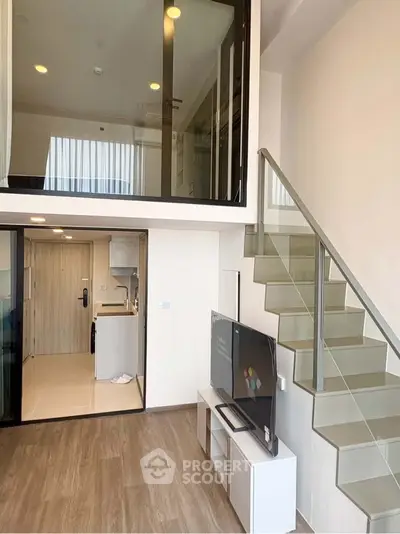 Modern loft apartment with sleek staircase and open living area, featuring high ceilings and contemporary design.