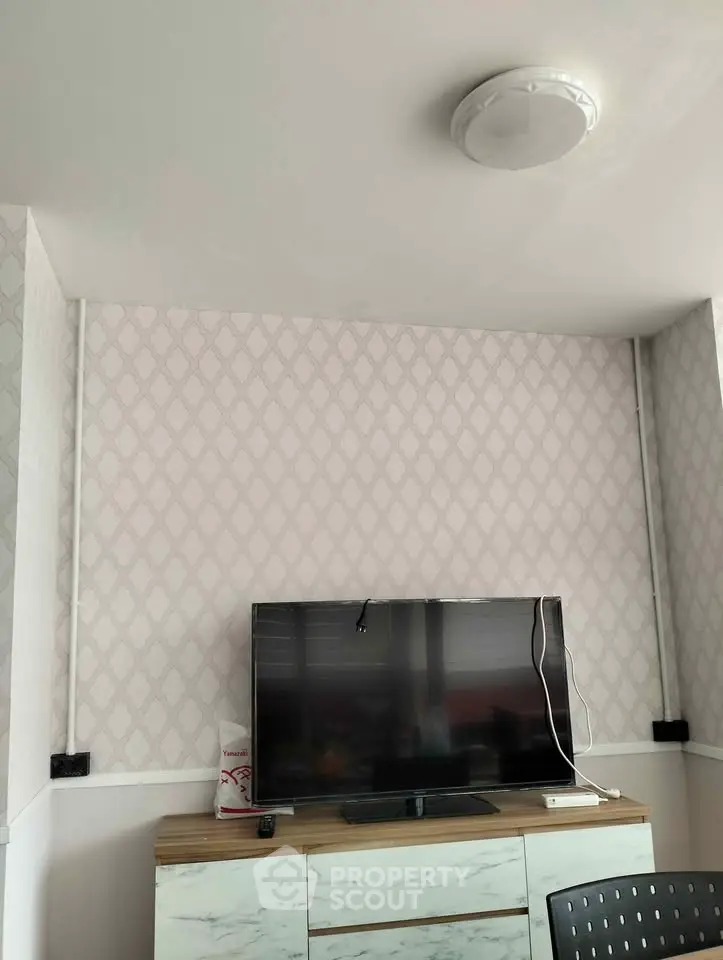Modern living room with stylish wallpaper and flat-screen TV on a sleek console.