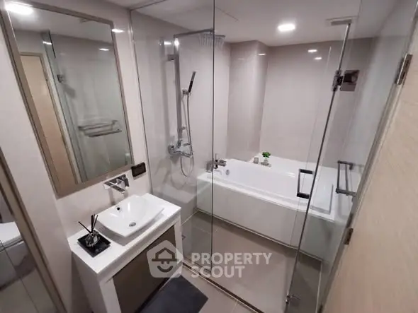 Modern bathroom with glass shower and bathtub in sleek apartment