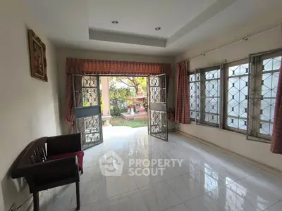 Spacious living room with large windows and garden view, perfect for relaxation and entertaining.