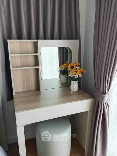 Chic vanity setup with mirror and floral decor in a cozy bedroom corner.