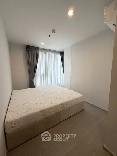 Cozy bedroom with large window and modern decor in a stylish apartment.