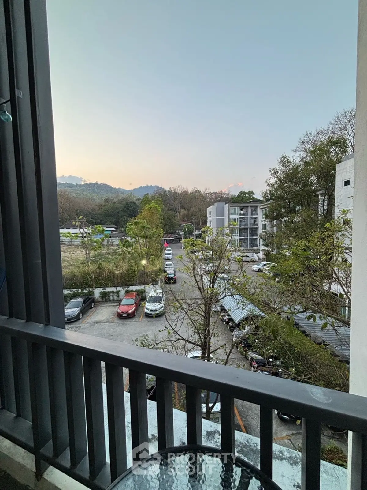 Scenic view from balcony overlooking parking area and lush greenery